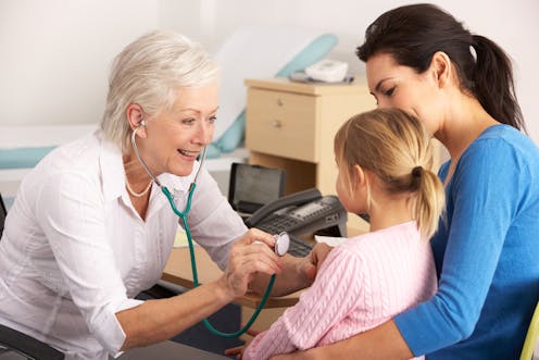 A doctor examines a young patient's chest with a stethoscope. 